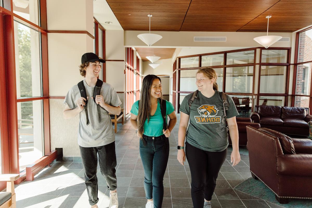 三个澳门威尼斯人网址的学生走在校园里，谈笑风生.